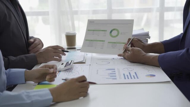 Young businessman, Asian stock trader agent or sales tax credit broker, brief introduction and pointing hand to graph report. Discuss with clients at desks showing budget charts or legal results.