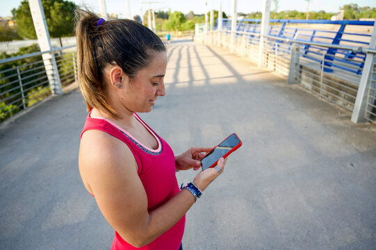 Beautiful woman using cell phone before going for a run outdoors