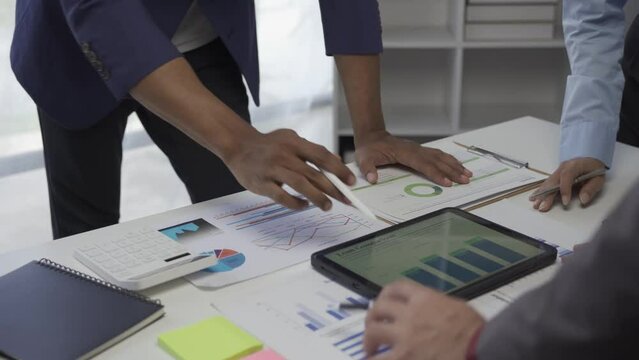 Young businessman, Asian stock trader agent or sales tax credit broker, brief introduction and pointing hand to graph report. Discuss with clients at desks showing budget charts or legal results.