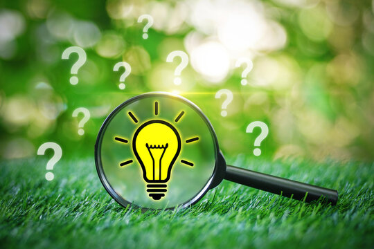 Magnifying glass focused on Light bulb symbol and question mark on the grass in garden with green nature background for choosing process solution problem solving. - Powered by Adobe
