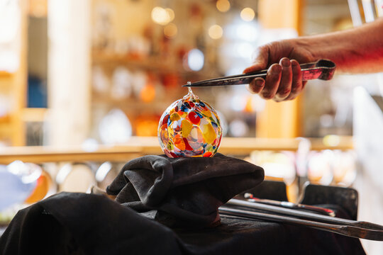 Glassblower crafting a Christmas bauble, from the heat of the oven to shaping it. Workshop based in France.