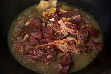 a hot oil and raw meat in a pan cooking slowly