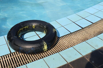 A buoy made of black tires lying against a swimming pool background