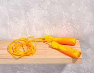 Minimalistic sports composition. A bright yellow jump rope lies on the table. Copy space for text.
