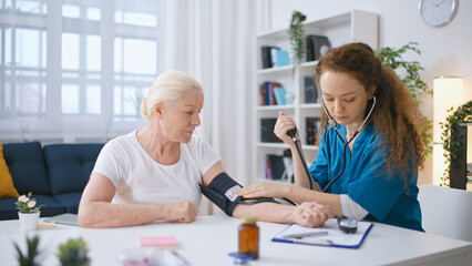 Woman therapist measuring blood pressure of a senior woman, health check-up - obrazy, fototapety, plakaty