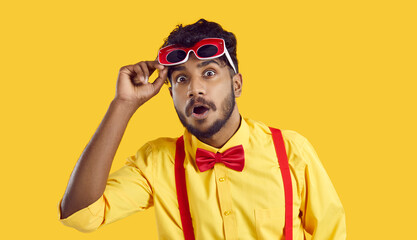 Funny surprised indian guy looking at you with shocked expression on orange background. Eccentric...