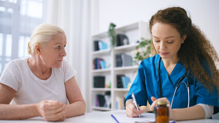 Young woman physician prescribing dietary supplements to senior woman at home - obrazy, fototapety, plakaty