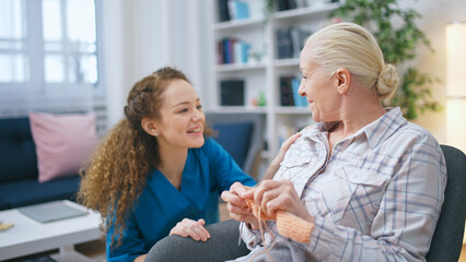 A young nurse visits a senior lady in a nursing home, inquiring about her well-being