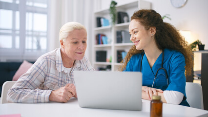 Female doctor teaching senior patient how to book a appointment with a doctor online