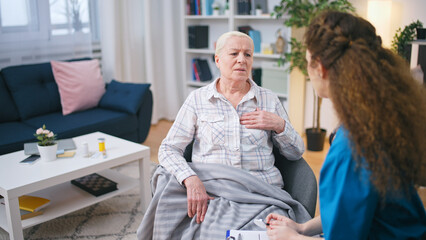 A senior woman complains to the visiting doctor about heart pain and arrhythmia