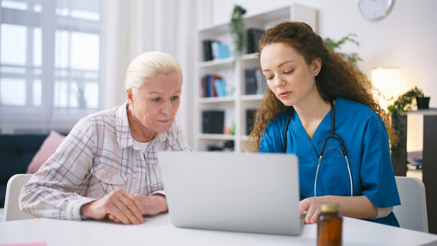 Friendly nurse showing senior woman how to book appointment with a doctor online
