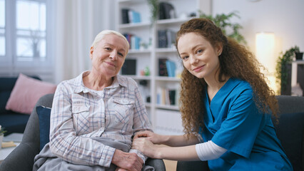 Female nurse holding hands of a senior woman, support and care for elderly people