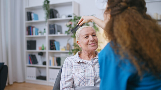 Medical worker combing hair of a senior woman in assisted living facility