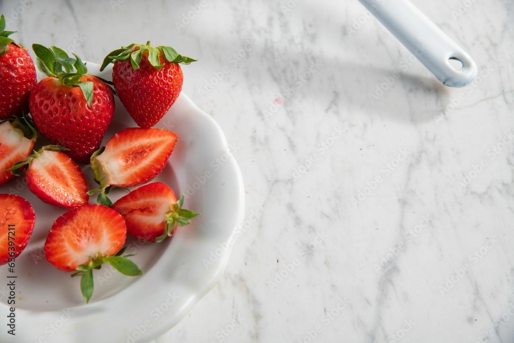 Wall mural Top view of a bowl with juicy red strawberries on a white marble table