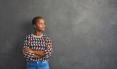 Portrait of attractive young African American woman who is thoughtfully smiling while standing...