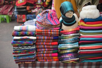 Vibrant display of multicolored scarves arranged in a pile at a bustling market in Peru