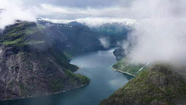 Male Hiker overlooking Norwegian Fjord and Mountains on a cloudy day 