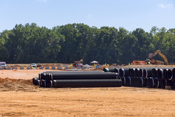 Stacks of large black plastic sewerage pipes are waiting to be installed on the industrial...