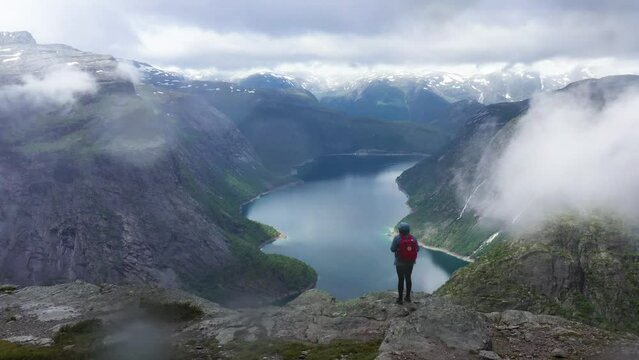 Female Hiker in Norway overlooking the Mountains and Fjord on a cloudy day