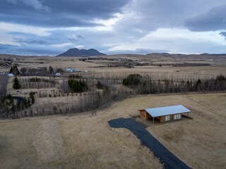 Single-family home  situated in a vast grassy meadow in front of a majestic mountain range