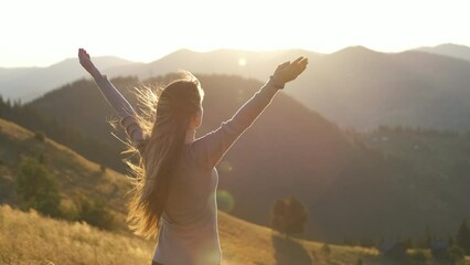 Young woman hiker standing alone with outstretched arms on mountain footpath enjoying view of evening nature on wilderness trail. Active way of life concept