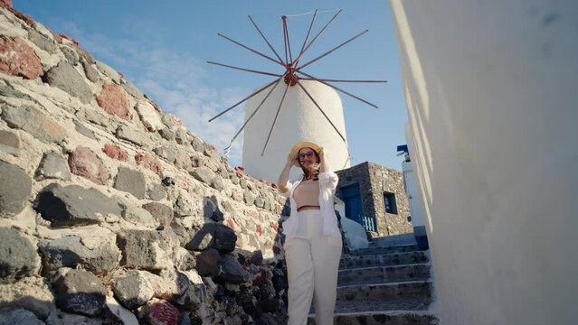 Tourist travel woman in Oia, Santorini, Greece. Happy tourist walking on stairs by famous landmark destination in Greece Santorini
