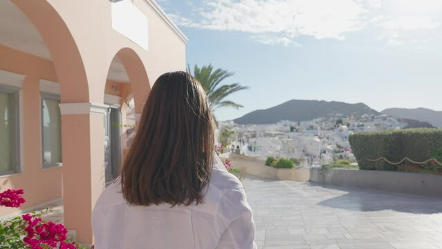 Tourist travel woman in Oia, Santorini, Greece. Happy tourist walking on stairs by famous landmark destination in Greece Santorini
