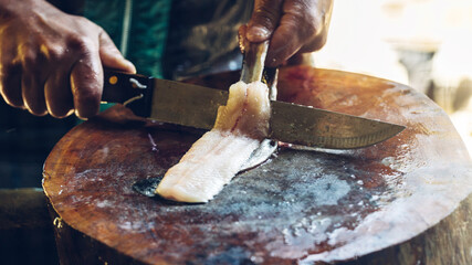 The sturgeon is in the hands of the experienced chef. He is using a knife to slice sturgeon fillet...