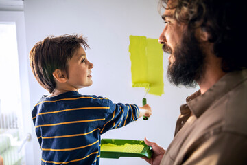 Young father and son painting a wall at home