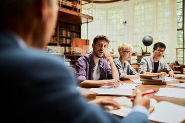 Young and diverse group of students studying and listening to their professor