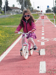 Bambina in bicicletta sulla pista ciclabile