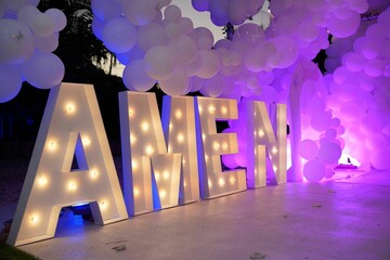 Decorative lights with the word 'Amen' and balloons in purple hues for an event - obrazy, fototapety, plakaty