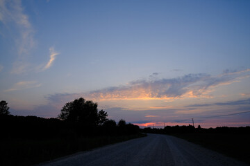 beautiful colorful Latvia country road landscape with trees, blue sky and colorful clouds in summer sunset light