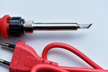 Red soldering iron on a white background. A tool for repairing electronics.