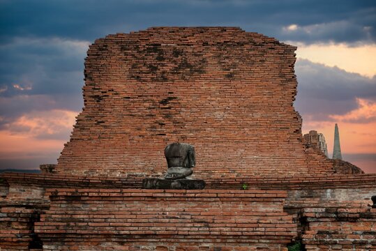Ancient brick wall with an old headless Buddha statue