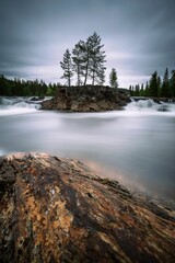 an island surrounded by trees and water is surrounded by a large rock