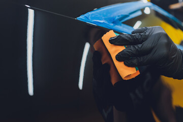 Car detailing - Man applies nano protective coating to the car. Selective focus.