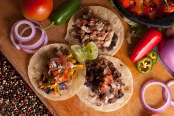 Top view of tacos with vegetables on a wooden cutting board