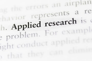 Close-up of a textbook with the term 'applied research' highlighted and focused