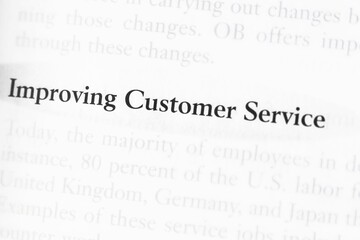 Close-up of a business textbook with the term 'improving customer service' highlighted and focused