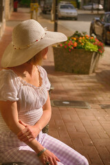 Middle-aged woman with summer hat patiently waits.