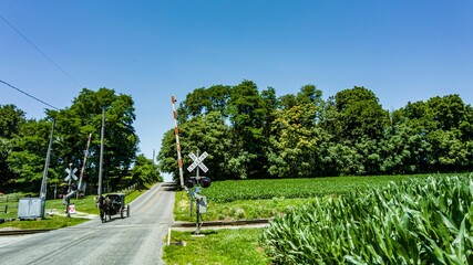 a large dirt road with a railroad crossing sign in the middle