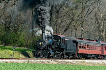 a train riding along the tracks on a clear day with a lot of smoke coming