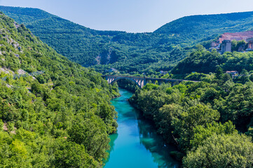 Fototapeta na wymiar A view down the Soca river towards the largest stone arch railway bridge at Solkan in Slovenia in summertime