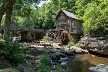 Wooden house with a cascading stream running through a lush green forest in Babcock State Park