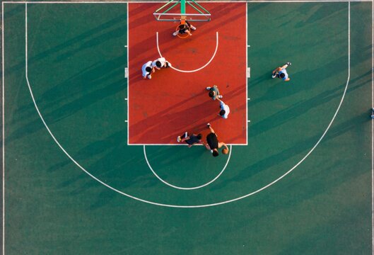 Aerial view of people playing a game of basketball on an outdoor court