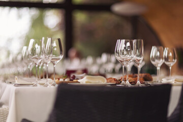 Busy restaurant, a table set in the restaurant. White tablecloths, glasses and shot glasses, close-up, selective focus, people talking in the background, indoors at daylight.