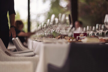 Busy restaurant, a table set in the restaurant. White tablecloths, glasses and shot glasses, close-up, selective focus, people talking in the background, indoors at daylight.