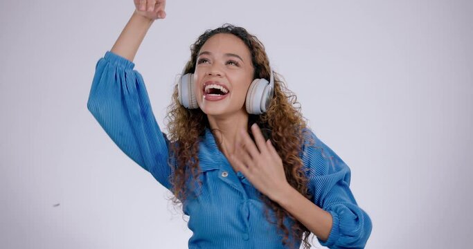 Face of woman, headphones and dance in studio for freedom, celebrate party and energy on white background. Portrait of happy model dancing to music, streaming sound and listening to audio on radio