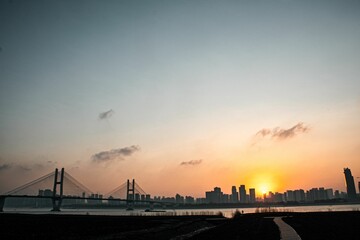 Fototapeta na wymiar Beautiful sunset over the Ehuang Yangtze River Bridge with a cityscape in the background in China